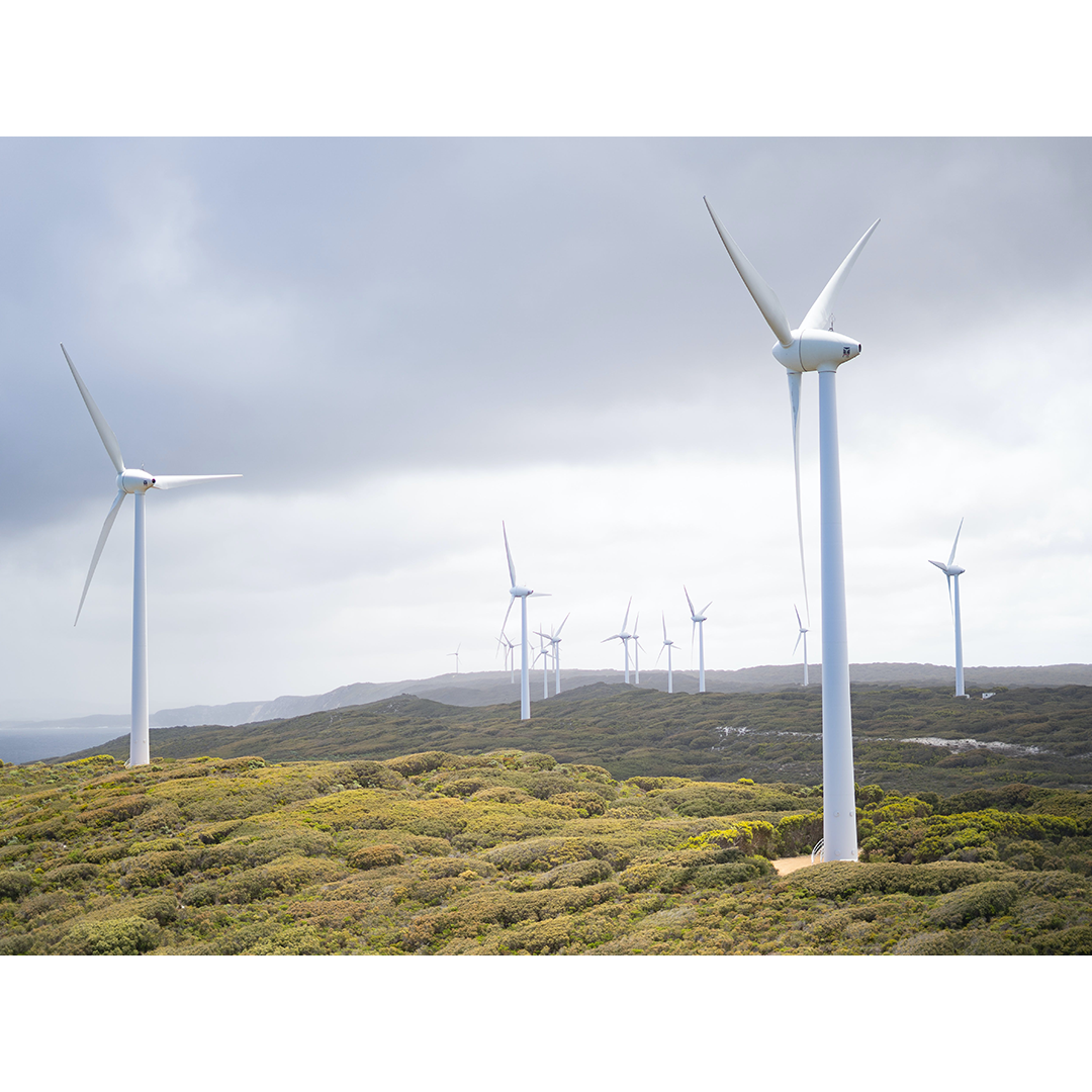 Photo by Harry Cunningham of wind turbines under a cloudy sky