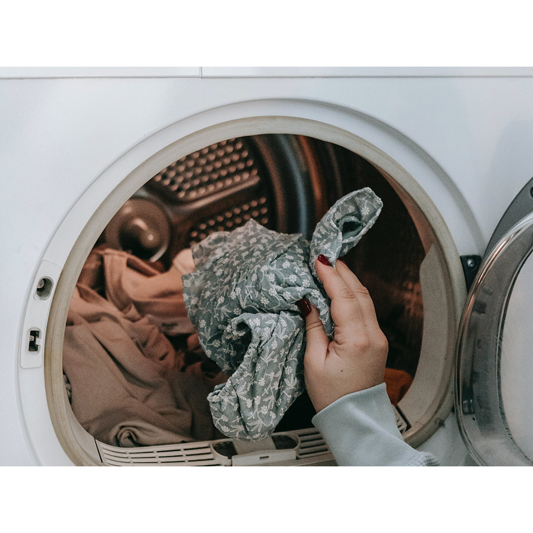 Photo by Sarah Chai of a woman putting clothes in the washing machine