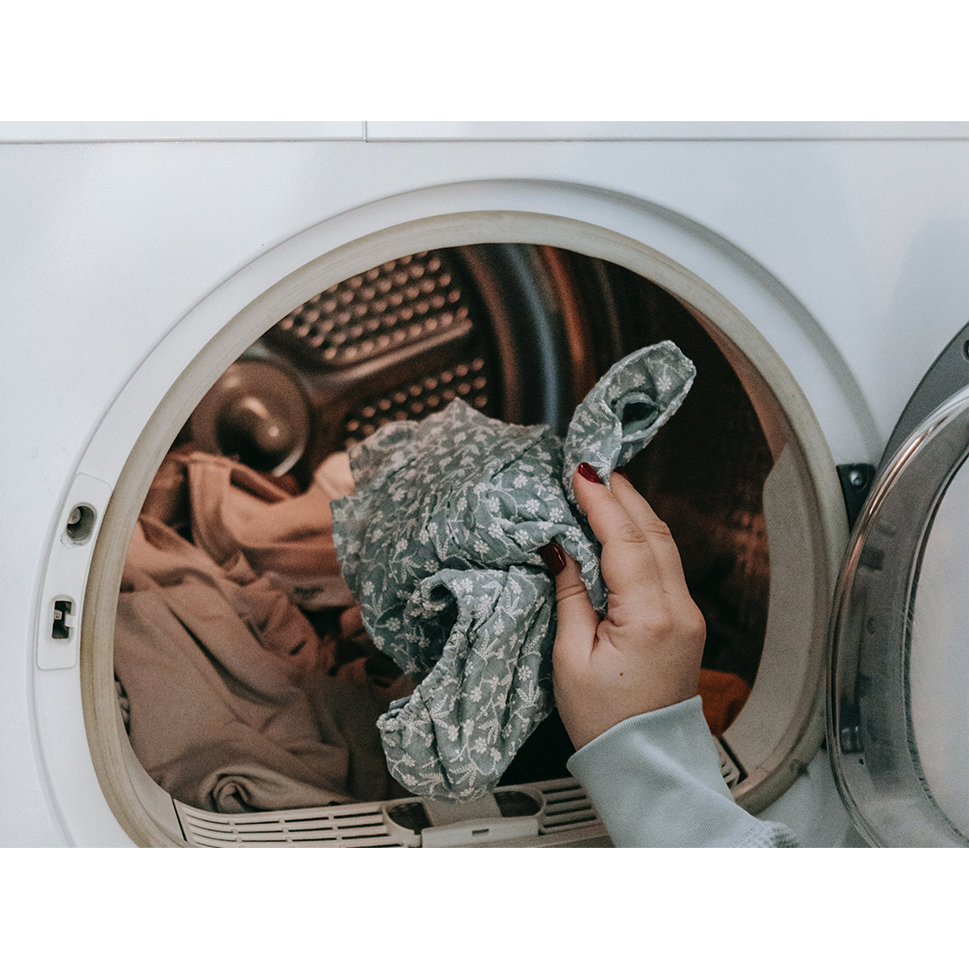 Photo by Sarah Chai of a woman putting clothes in the washing machine 